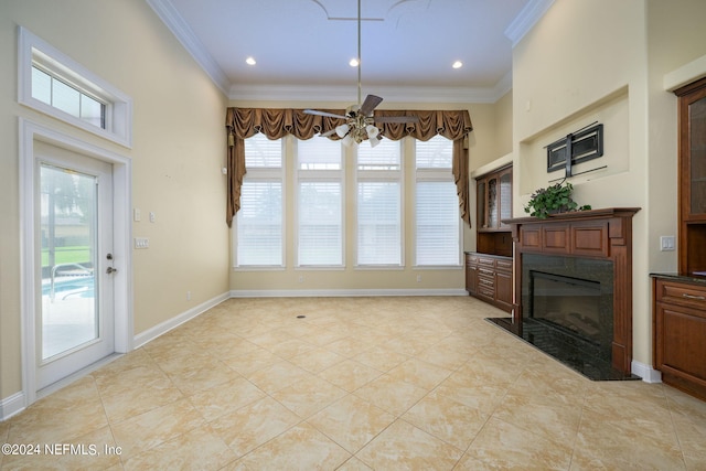 unfurnished living room featuring crown molding, a wealth of natural light, a fireplace, and ceiling fan