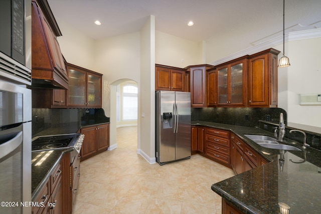 kitchen featuring decorative backsplash, custom range hood, hanging light fixtures, sink, and stainless steel fridge