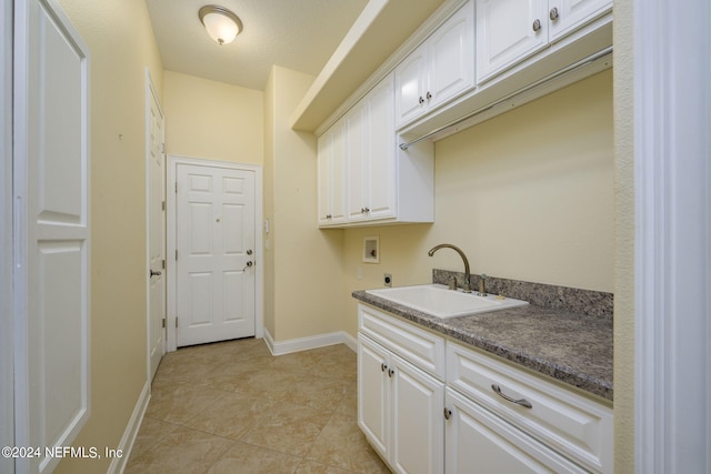 washroom featuring washer hookup, hookup for an electric dryer, sink, light tile patterned flooring, and cabinets