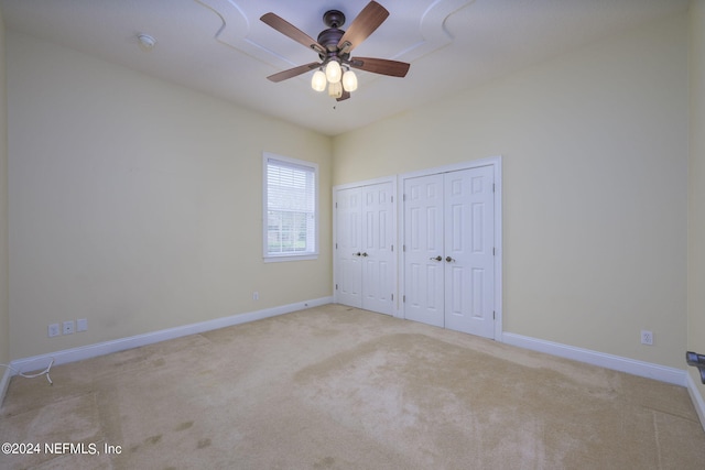 unfurnished bedroom featuring ceiling fan, two closets, and light colored carpet