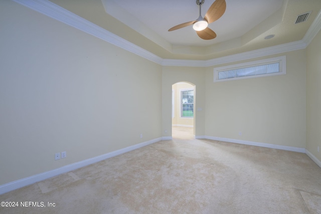 unfurnished room with ornamental molding, light carpet, a tray ceiling, and ceiling fan