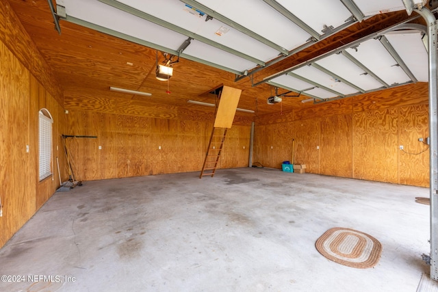 garage featuring a garage door opener and wooden walls