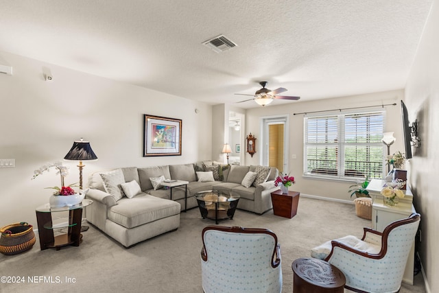 carpeted living room featuring ceiling fan and a textured ceiling