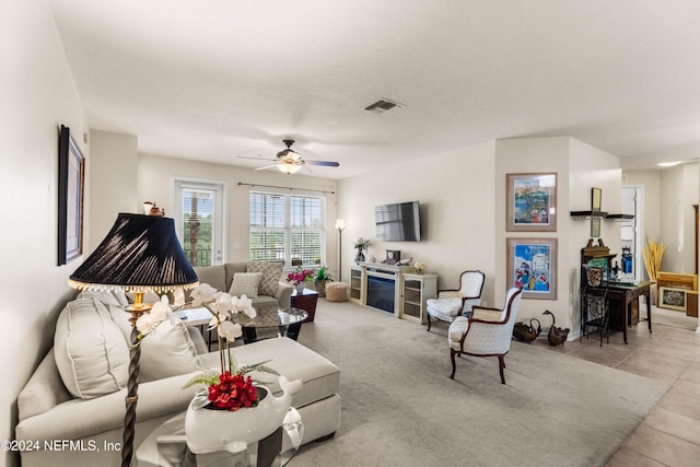 tiled living room with a textured ceiling and ceiling fan