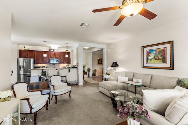 carpeted living room featuring ornate columns, a textured ceiling, and ceiling fan