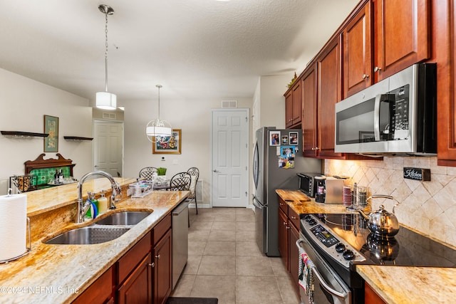 kitchen with light tile patterned flooring, sink, appliances with stainless steel finishes, light stone countertops, and pendant lighting