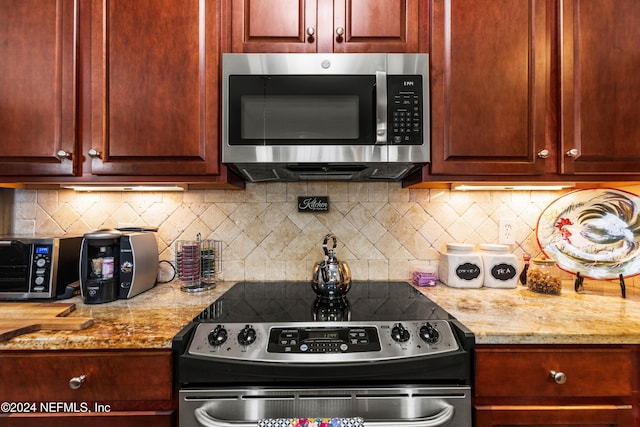 9831 Del Webb Pkwy Unit 2308, Jacksonville, FL 32256 - kitchen featuring stainless steel appliances, decorative backsplash, light stone countertops, and dark brown cabinets