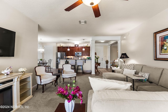 carpeted living room with a textured ceiling and ceiling fan