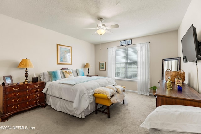 bedroom featuring ceiling fan, a textured ceiling, and light carpet