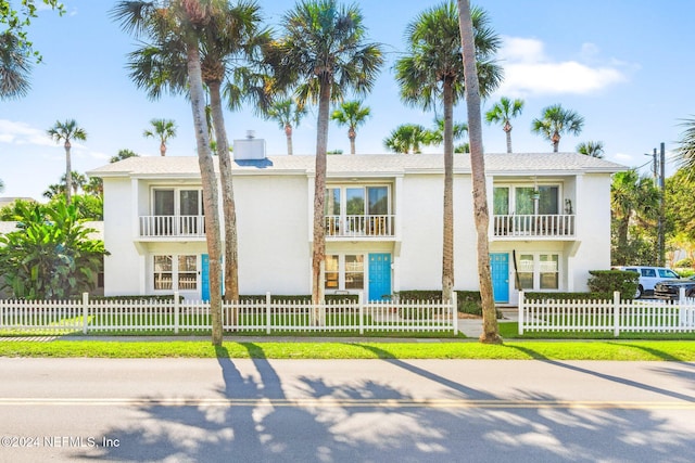 view of front of house featuring a balcony and a front lawn