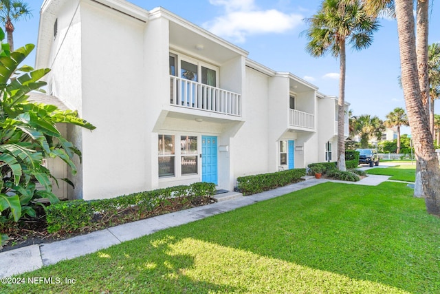 view of front of property featuring a balcony and a front lawn