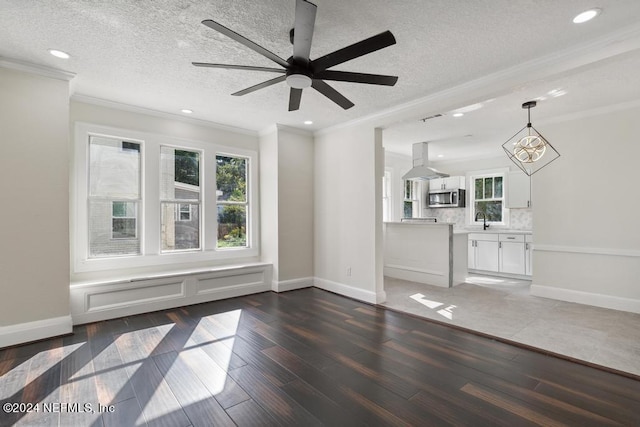 unfurnished living room with ceiling fan with notable chandelier, dark hardwood / wood-style flooring, a textured ceiling, sink, and crown molding