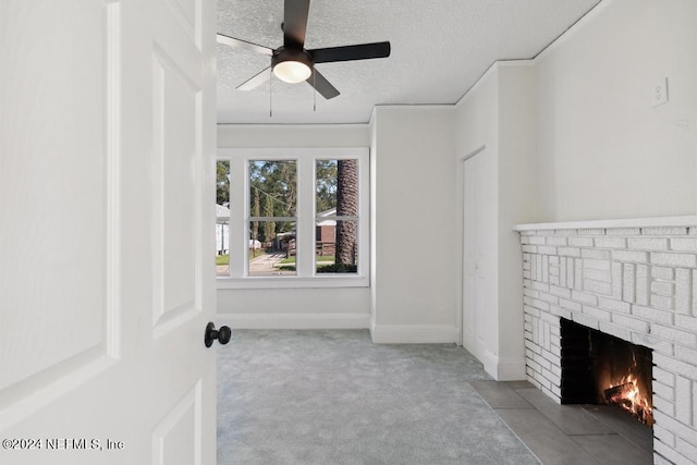 unfurnished living room with light carpet, ornamental molding, ceiling fan, a textured ceiling, and a fireplace