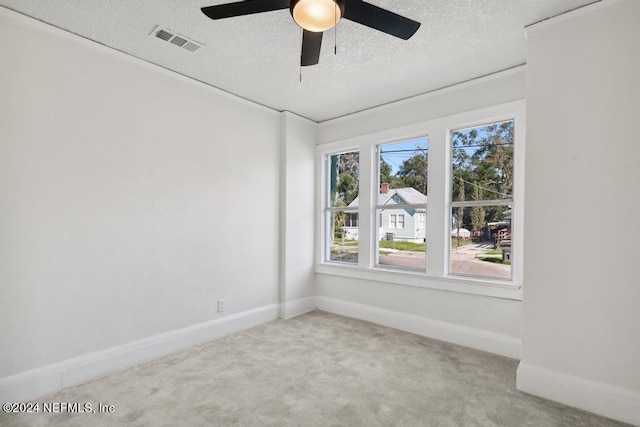 carpeted spare room featuring ceiling fan, a healthy amount of sunlight, and a textured ceiling