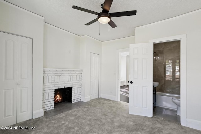 unfurnished living room with carpet floors, a textured ceiling, ornamental molding, ceiling fan, and a fireplace