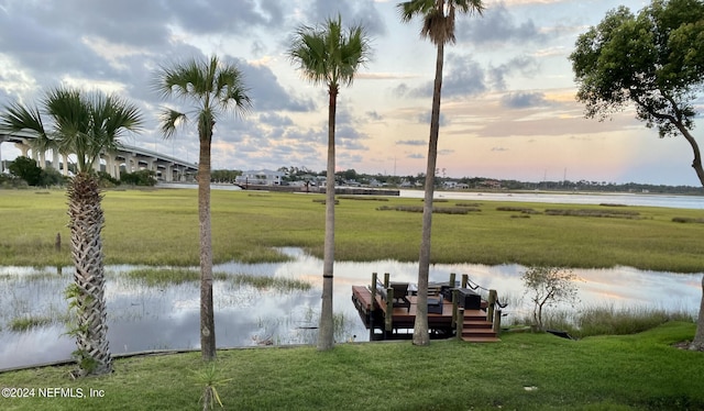 view of dock with a yard and a water view