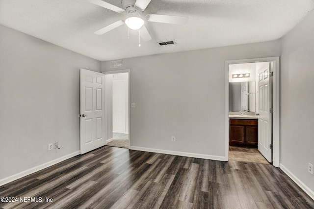 unfurnished bedroom with ensuite bathroom, sink, a textured ceiling, ceiling fan, and dark wood-type flooring