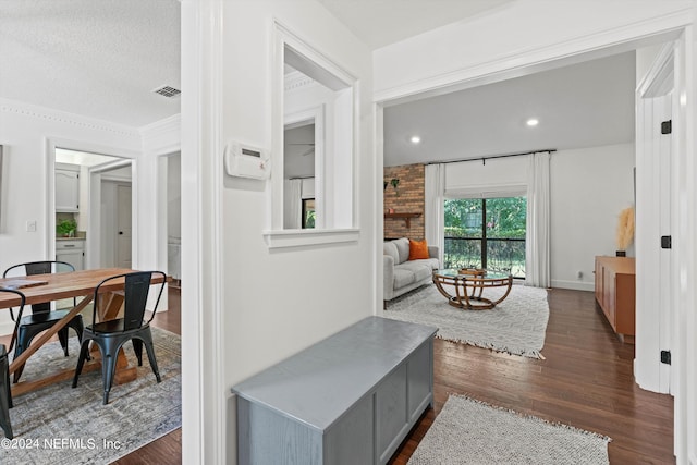 corridor featuring crown molding, a textured ceiling, and dark hardwood / wood-style flooring