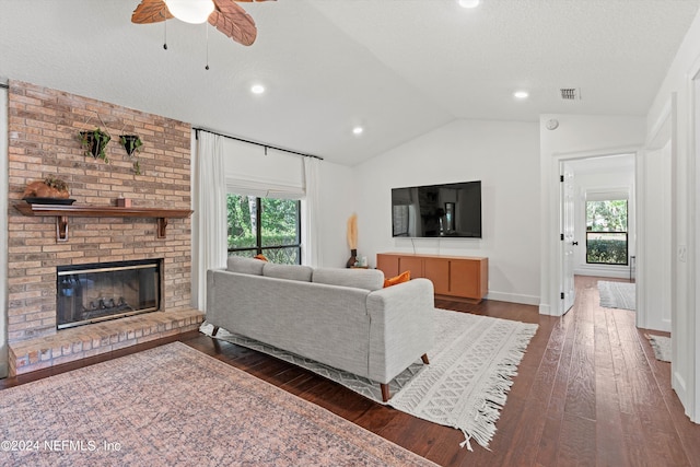 living room featuring a fireplace, lofted ceiling, a wealth of natural light, and dark hardwood / wood-style floors