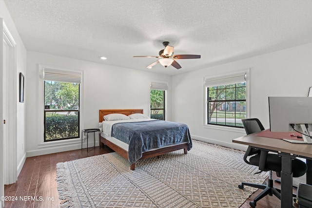 bedroom with multiple windows, a textured ceiling, ceiling fan, and dark hardwood / wood-style flooring