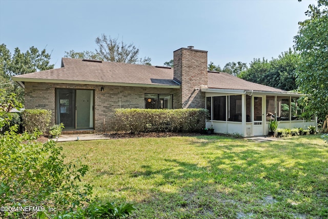 rear view of property featuring a lawn and a sunroom