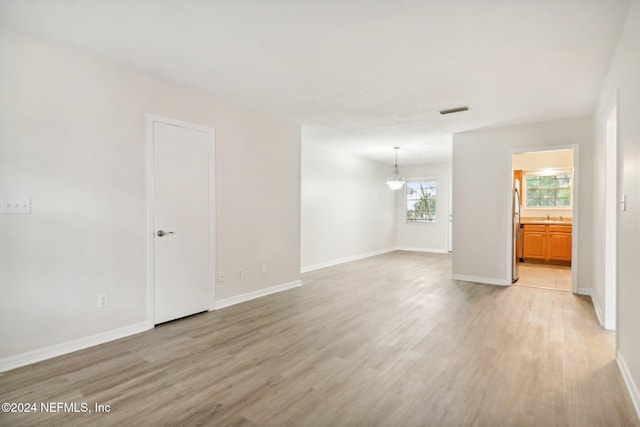 empty room featuring an inviting chandelier, sink, and light hardwood / wood-style flooring