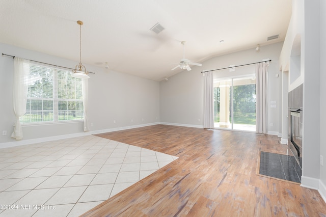 unfurnished living room with ceiling fan, lofted ceiling, light hardwood / wood-style flooring, and plenty of natural light