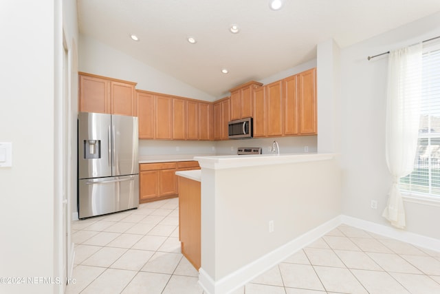 kitchen with appliances with stainless steel finishes, lofted ceiling, kitchen peninsula, and a wealth of natural light