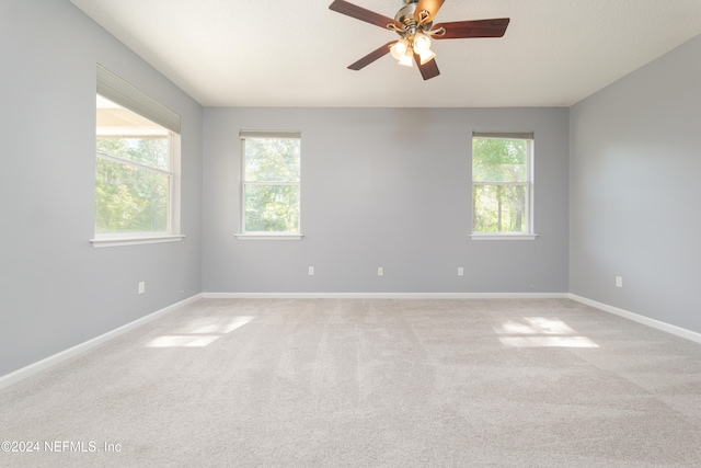 carpeted spare room featuring a wealth of natural light and ceiling fan