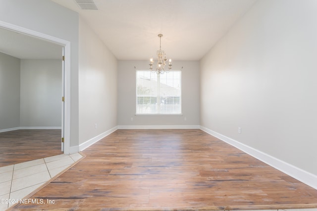 unfurnished dining area featuring a chandelier and hardwood / wood-style flooring