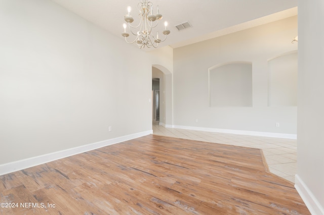 spare room featuring light hardwood / wood-style floors and a chandelier