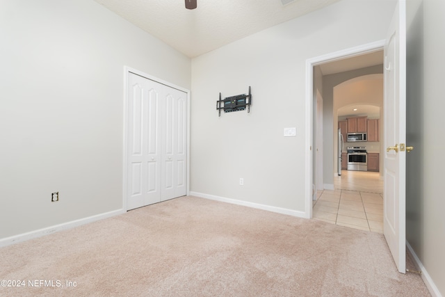 unfurnished bedroom featuring a closet, ceiling fan, and light colored carpet