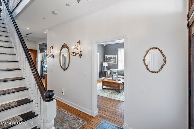 stairs with ornamental molding and hardwood / wood-style floors