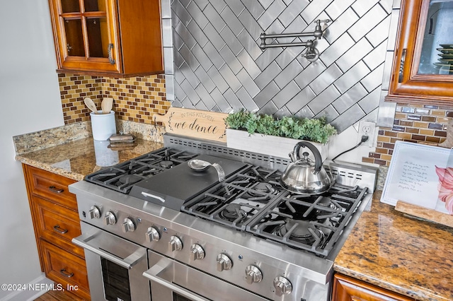 kitchen featuring stone counters, backsplash, and high end stainless steel range