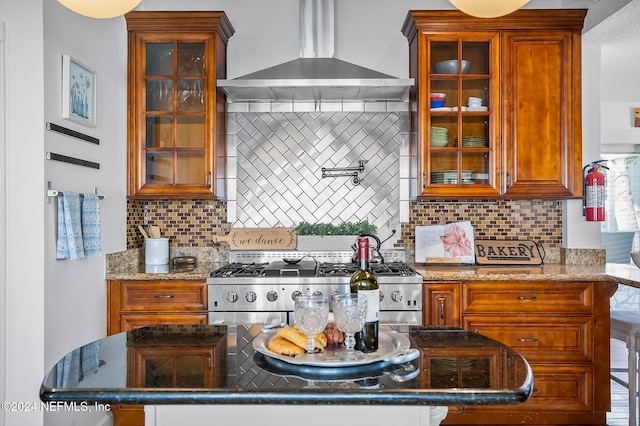 kitchen with backsplash, a kitchen breakfast bar, light stone countertops, stainless steel range oven, and wall chimney exhaust hood