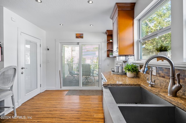 kitchen with light hardwood / wood-style flooring, tasteful backsplash, sink, and plenty of natural light