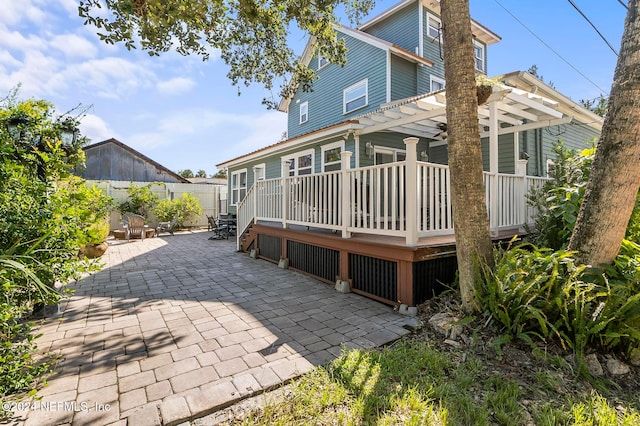 back of property with a wooden deck, a patio, and a pergola