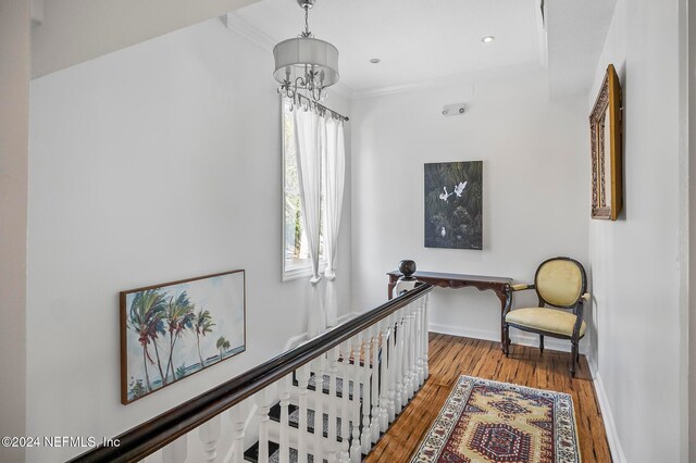 hallway featuring ornamental molding, a chandelier, and hardwood / wood-style flooring