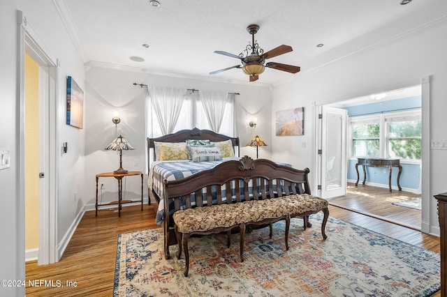 bedroom featuring multiple windows, ornamental molding, hardwood / wood-style flooring, and ceiling fan