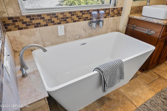 bathroom with vanity, tile walls, and a bath