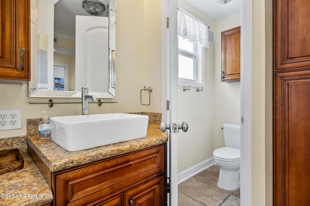 bathroom with toilet, vanity, and tile patterned floors