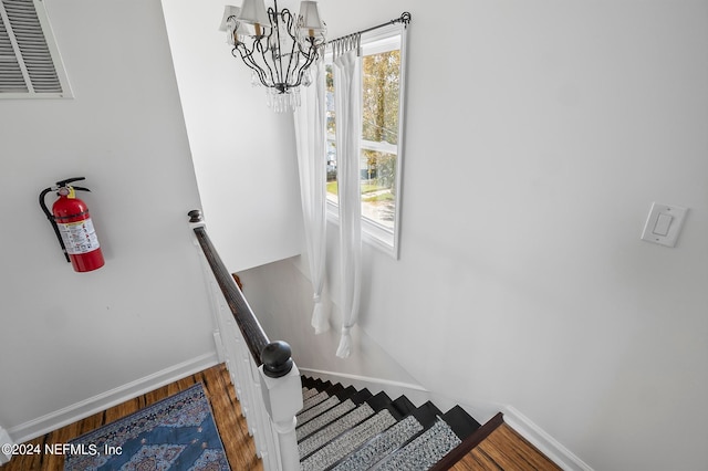 staircase with wood-type flooring and a chandelier