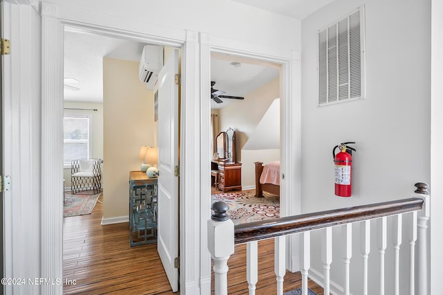 hallway with a wall mounted AC and hardwood / wood-style floors