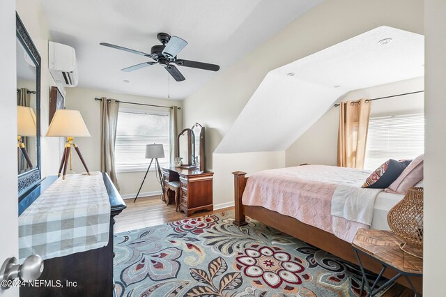 bedroom featuring ceiling fan, a wall mounted AC, and light hardwood / wood-style flooring