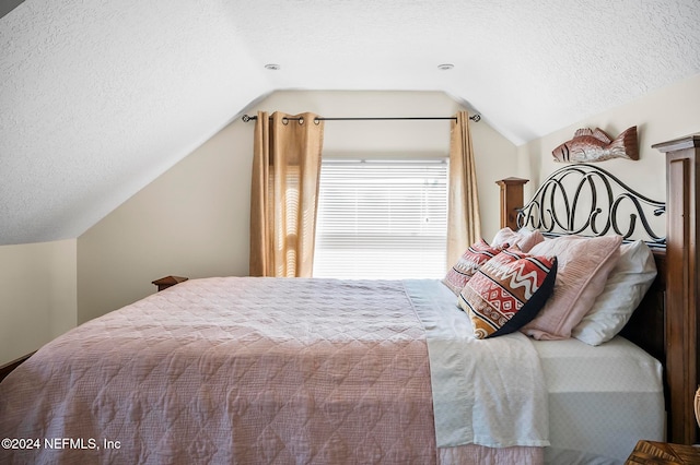 bedroom with a textured ceiling and lofted ceiling