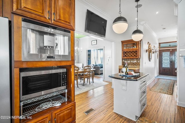 kitchen with backsplash, ornamental molding, light wood-type flooring, and hanging light fixtures