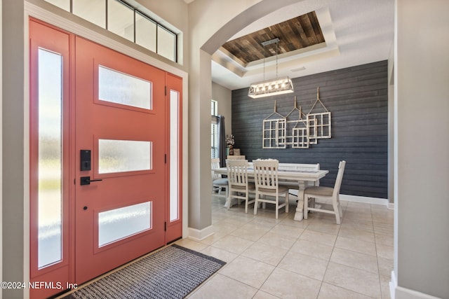 entrance foyer featuring a raised ceiling, wooden ceiling, light tile patterned floors, and plenty of natural light