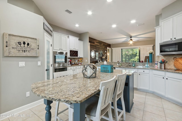 kitchen with appliances with stainless steel finishes, a breakfast bar area, and white cabinets