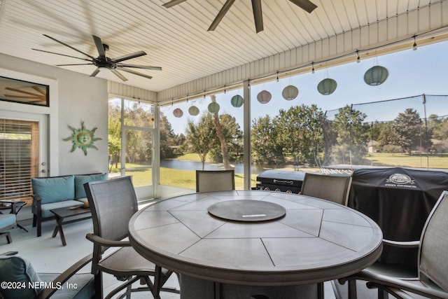 sunroom with a water view and ceiling fan