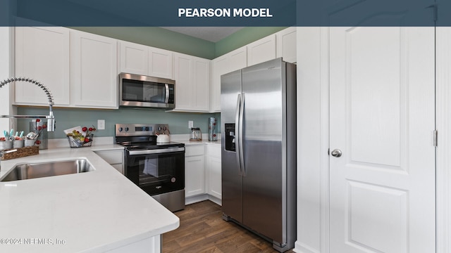 kitchen featuring stainless steel appliances, dark wood-type flooring, a sink, light countertops, and white cabinets